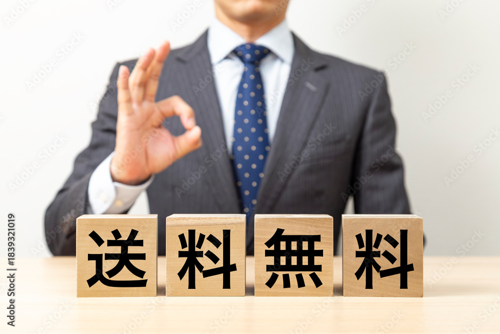 Obraz premium 「送料無料」と書かれたブロックとOKポーズをするビジネスマン