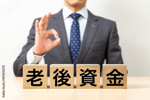 「老後資金」と書かれたブロックとOKポーズをするビジネスマン