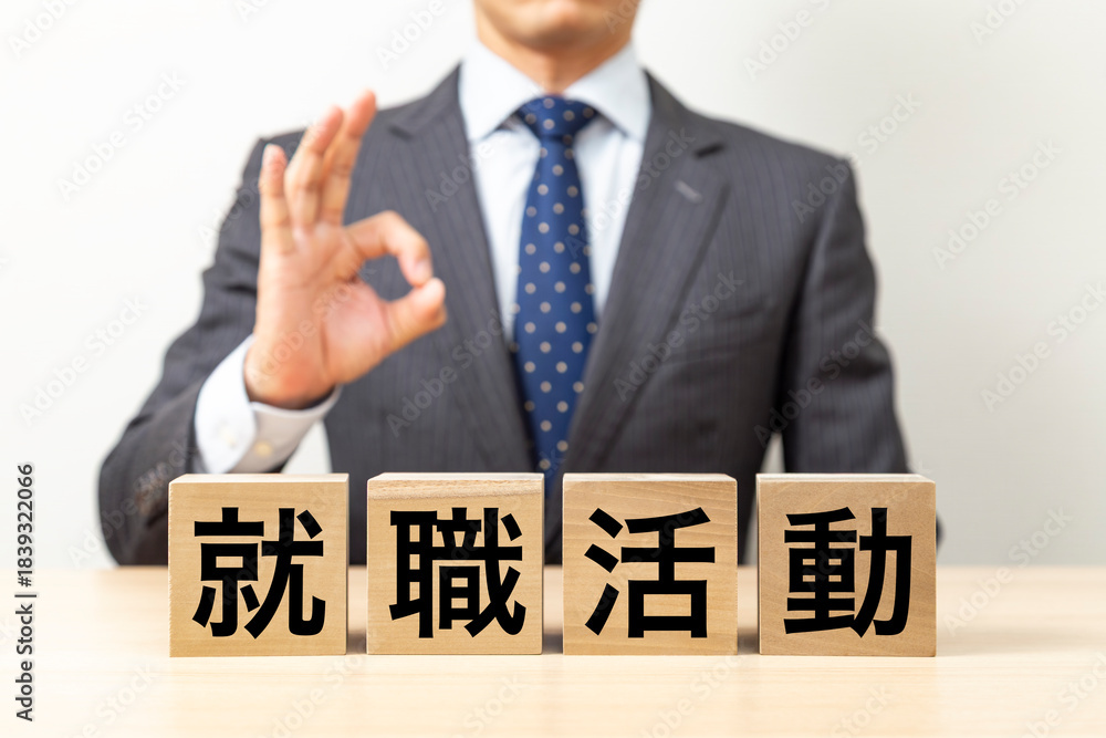 Obraz premium 「就職活動」と書かれたブロックとOKポーズをするビジネスマン