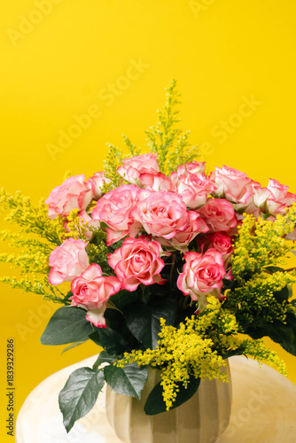 Arreglo floral de rosas rosadas sobre fondo amarillo minimalista