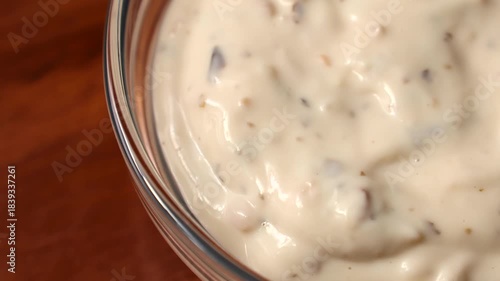 Creamy homemade mushroom dipping sauce in a glass bowl circle rotation on wooden background close up