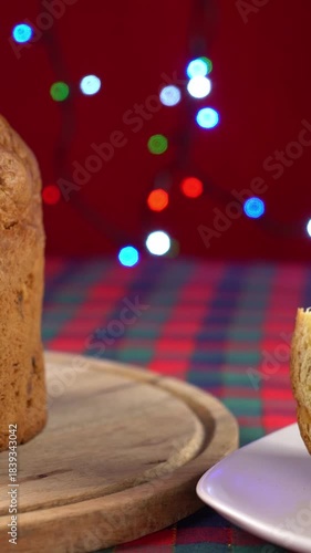 Panettone su tagliere, fetta di panettone sul piatto, luci colorate sullo sfondo