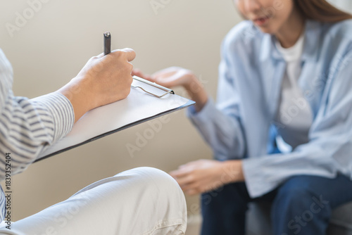 Psychology, depression. Suffer asian young woman consultation with psychologist while patient counseling mental therapy, doctor hand taking notes at clinic. Psychologist with sick mental health person