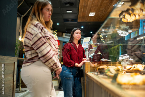 Canvas Print Gen z young women choosing pastries in cafe