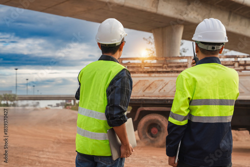 Konstfotografi Construction Workers Observing Progress on a Roadway Project Under a Bridge Duri