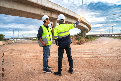Construction Workers Overseeing Urban Infrastructure Development Under a Cloudy Sky