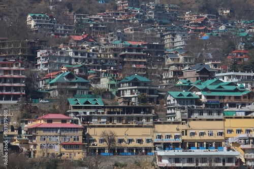 Colorful Rooftops Over Shimla SlopesPanoramic view of hillside structures with green, red, and yellow rooftops in Shimla, showing the charm of a mountain city.