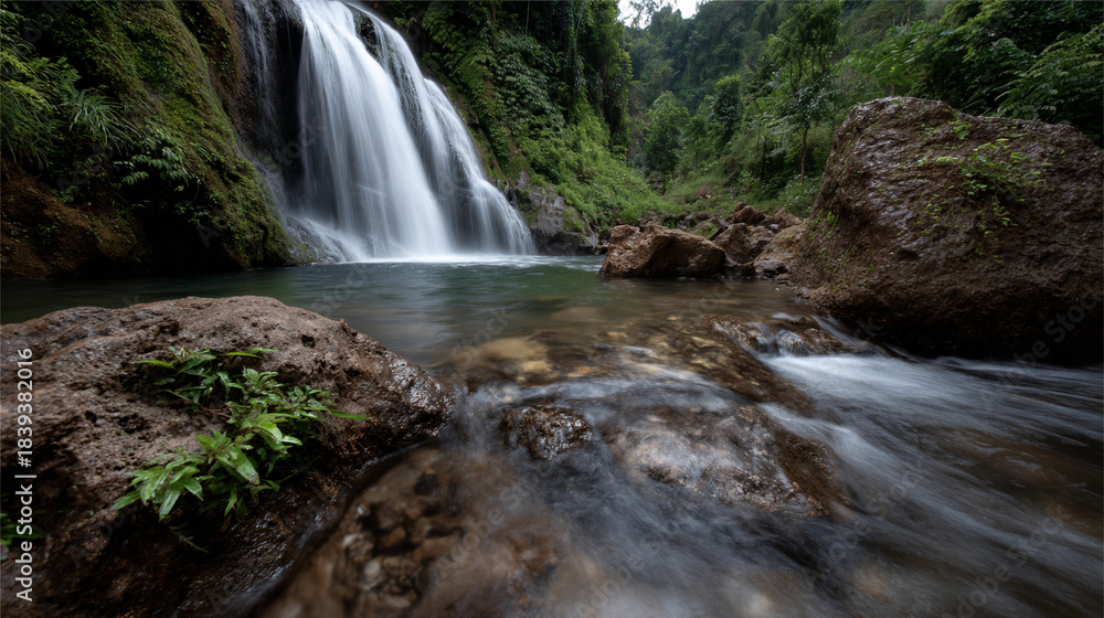 Fototapeta premium Lush jungle waterfall cascading into a clear pool.