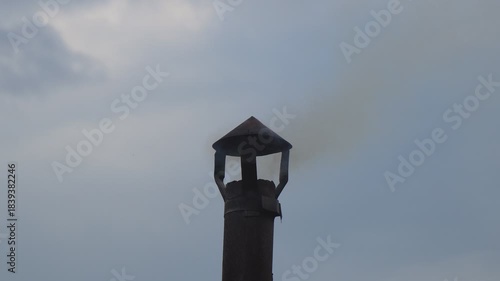 Smoke from a small chimney against a cloudy sky. A small rural bathhouse is being heated