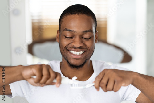 Fotografi Man happily brushes his teeth in a bright bathroom, enjoying his morning routine