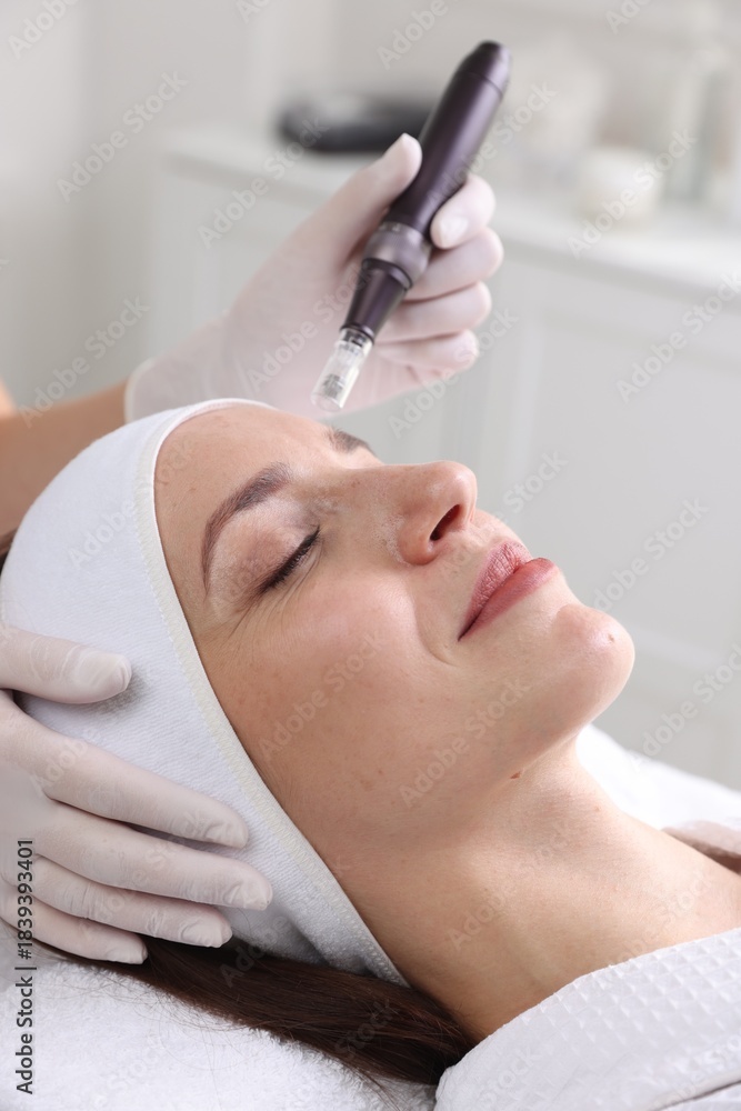 Fototapeta premium Woman undergoing microneedling procedure in beauty salon, closeup