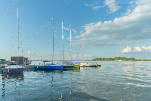 Sailboats docked at quiet marina under clear blue sky. Yachts moored quietly in the harbor, poised for new journeys beneath an endless sky of freedom and possibility.