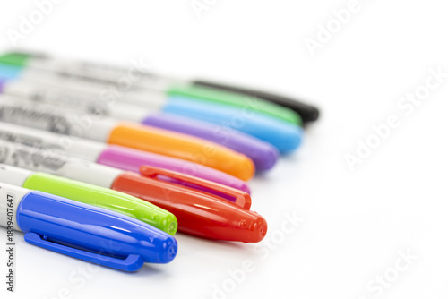 Close-up view of a set of colorful markers with caps on a clean white background showing various vibrant colors in a diagonal