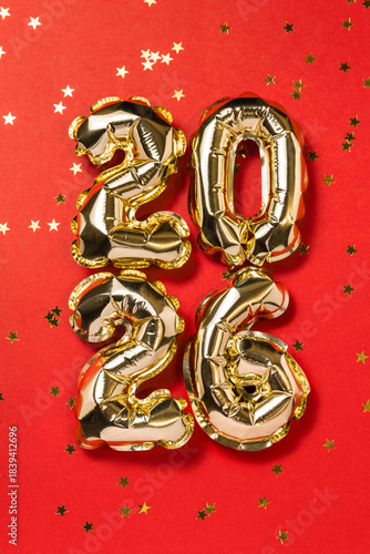 New year 2026 balloon celebration card. Gold foil helium balloon number 2026, party decoration, gold confetti stars on red background. Copy space, flat lay, merry christmas, happy holidays concept.