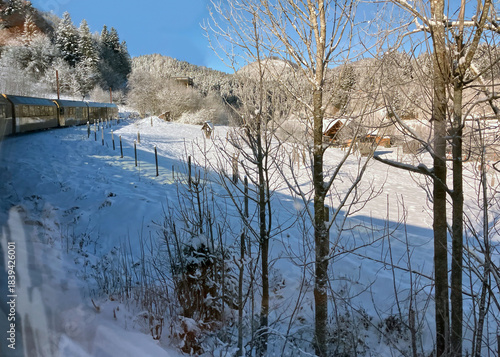 View from the window of a Himmelsstiege train on the railway line from Sankt Pölten to Mariazell into a snowy winter landscape with a blue sky, Austria