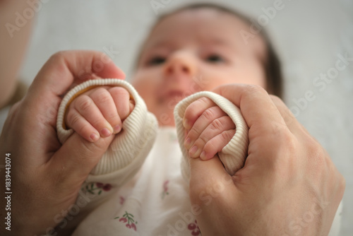 Close-up view of a newborn resting calmly as their small hands grasp a parent’s thumbs for comfort and connection.