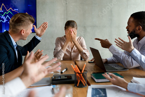 Foto In a tense corporate meeting, a group of coworkers shouts at a young businesswoman, pointing fingers and expressing frustration