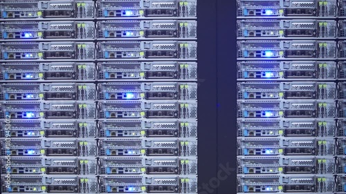 Slow motion of AI server racks blinking with blue LED lights in a dark room, showcasing high-performance computing infrastructure.