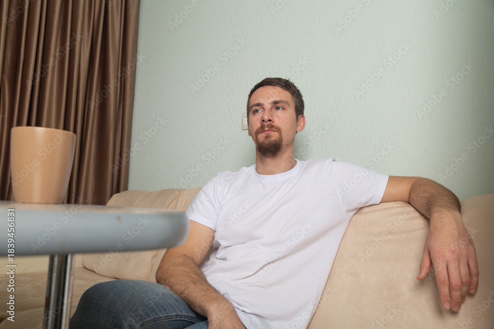 Fototapeta premium Man drinking coffee sitting on sofa at home