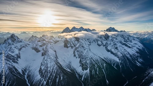 Majestic Snow Capped Mountain Range at Sunrise with Dramatic Clouds.
