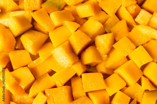 Peeled, ripe mango fruit pieces. Background texture.