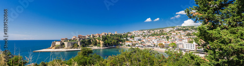 Panoramic view of Ulcinj, Montenegro, featuring the historic Old Town, sandy beaches, and hillside houses overlooking the blue Adriatic Sea under a clear summer sky.