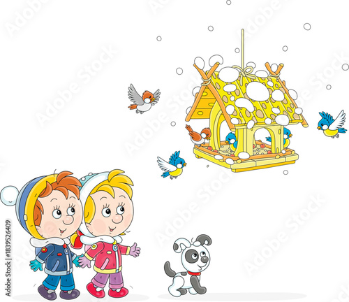 Happy little boy and girl with their puppy watching small birds merrily flying around a homemade birdfeeder on a snowy winter day, vector cartoon illustration isolated on a white background