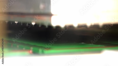 A close-up shot of a modern industrial machine automatically dispensing liquid chocolate filling into green empty molds on a conveyor belt, during the mass production process