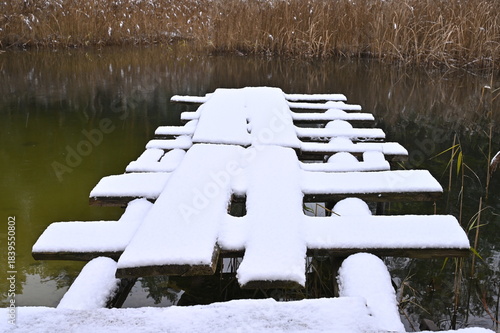 Wooden bridge for diving into water in late autumn in the snow.