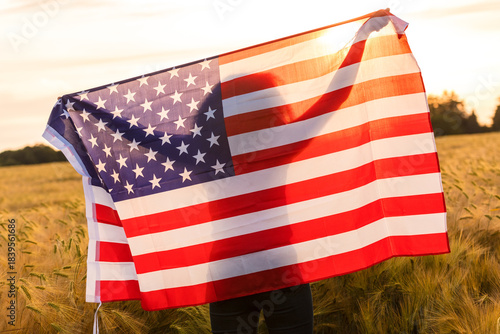 Silhouette of Young Woman Holding USA Flag in Field at Sunset