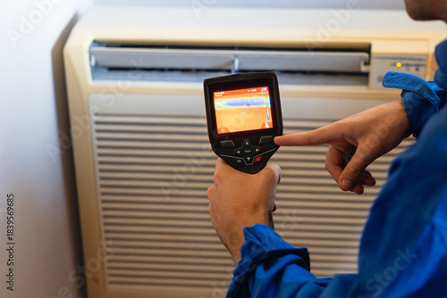Technician inspecting air conditioner with thermal camera