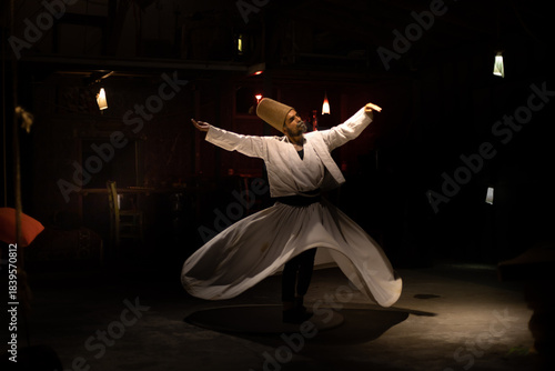 The image of a dervish performing a whirling dervish dance against a dark backdrop.