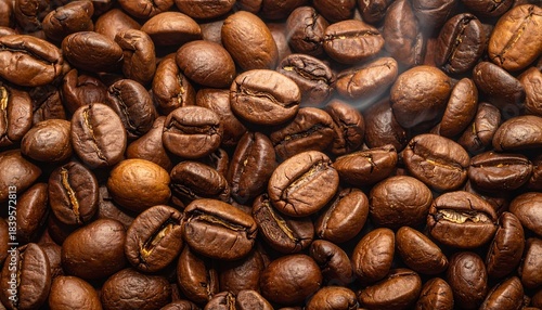 Roasted coffee beans form a warm-toned textured expanse with hints of light and visible oil sheen
