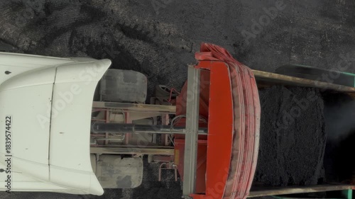 Top view of a tipper truck unloading hot asphalt on a construction site for road renewal