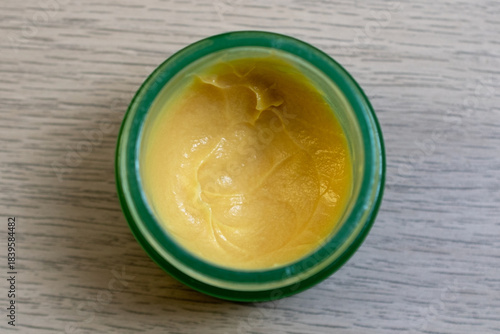 Open Jar of Yellow Cream on Wooden Surface
