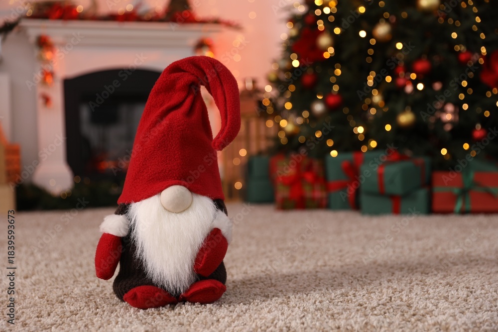 Fototapeta premium Cute Christmas gnome on floor against blurred lights indoors, closeup. Space for text