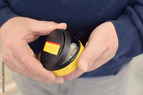 A man holds a box of snus. A box of snus pads replaces smokeless cigarettes. Swedish nicotine pouch