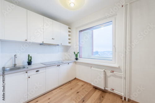 Modern White Kitchen Interior with Large Window and Wooden Flooring