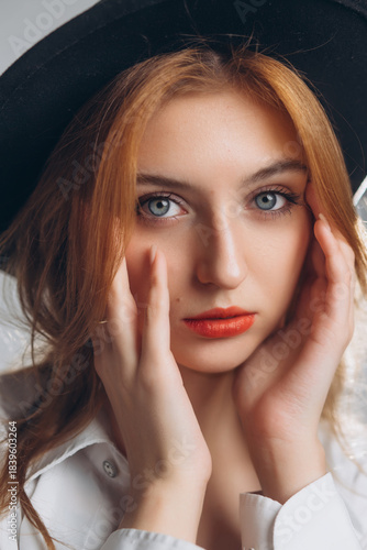 Obraz na płótnie Portrait of a Young Red-Haired Woman in a Black Hat