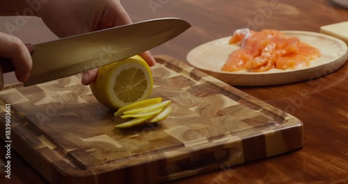 A woman with a belly confidently cuts a fresh lemon in a housewife's home kitchen. Freshness. Concept housewife woman hands cutting lemon applies cutlery, ingredient