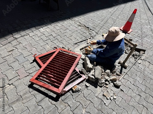 A worker changes a damaged Grid in the pave way in La Paz, Bolivia on a warm and sunny November day. 