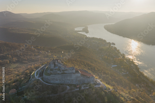 Visegrad, Hungary - Aerial panoramic drone view of the beautiful high castle of Visegrad on a moody autumn sunset. Danube Bend (Dunakanyar) and amazing golden sunset at background.