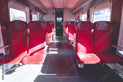Red, empty passenger seats in a modern regional train.