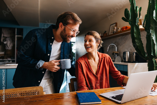 A couple chatting at the kitchen table with a laptop