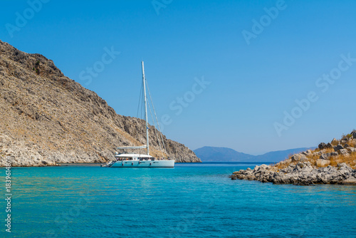 Yacht Boat Catamaran On Turquoise Sea In Bay Near Symi Greece. Sailing Travel Vacation Background