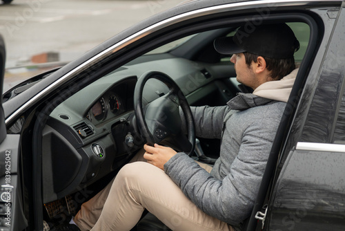 Male driver holding steering wheel of black car