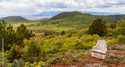 A cushioned chair perched to take in an extensive landscape view in Utah with mountains in the distance under a sky with white clouds. 