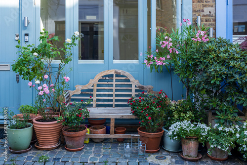 A pastel-coloured Victorian house front in affluent area of central London with lush front garden and potted plants.