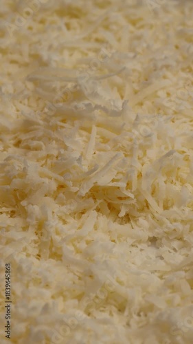 grated parmesan cheese, rotation in circle. fine grano padano shreds, Turning. vertical video. cooking ingredient