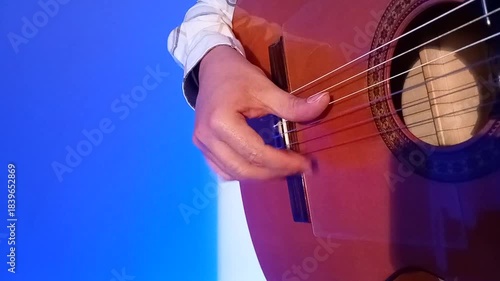 Close up of right hand a guitarist that strumming tremolo with acoustic guitar on blue room